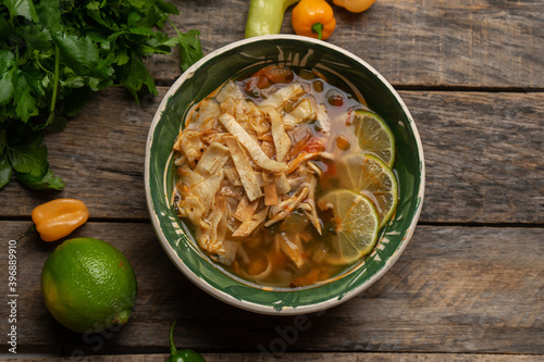 Mexican lime soup with chicken on wooden background photo