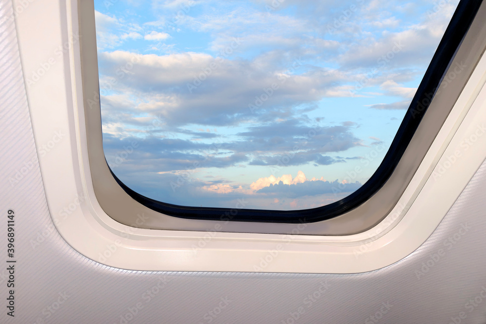 beautiful sky blue sky landscape with fluffy clouds behind the porthole of a plane, travel concept