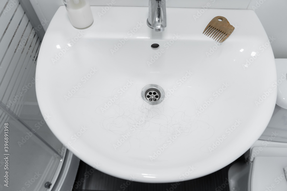 Fototapeta premium Hair loss. Hair in the sink after combing the head