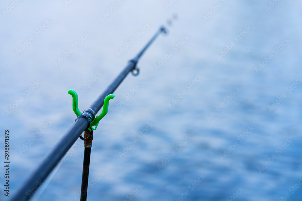 Fishing rod with a bell on the background of the river. Fishing hobby Fishing rod with a bell on the background of the river. Fishing hobby