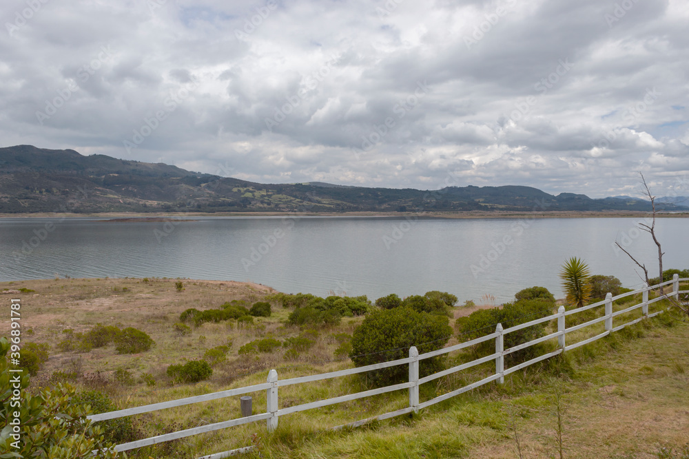 Colombian Tomine lake fall scene with mountains, wooden fence and white cloudy sky