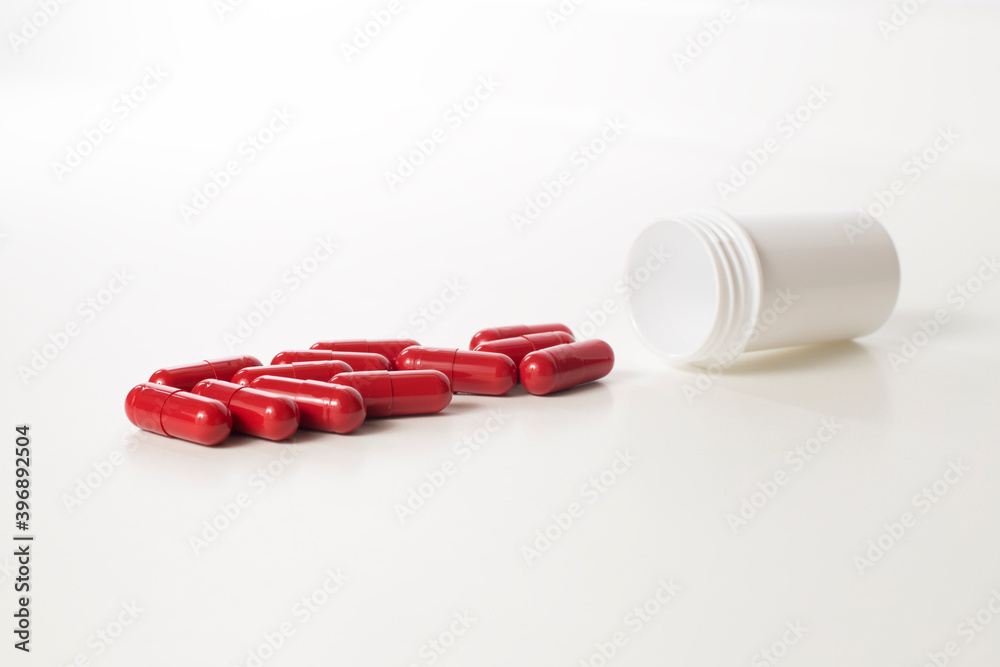 Red probiotics capsule and plastic bottle on white Red probiotics capsule and plastic bottle on white