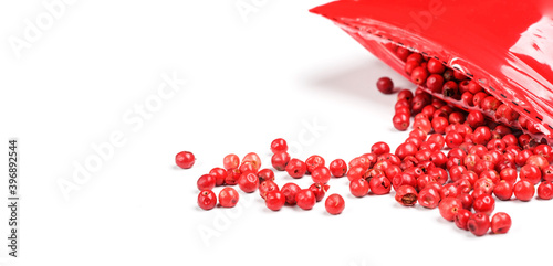 Pink peppercorns - dried fruits from peruvian peppertree ( Schinus molle ), with red plastic pack near, closeup detail from above photo