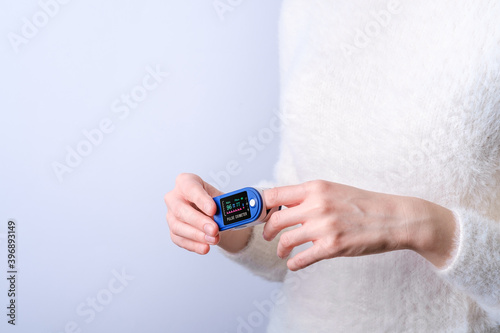 Person using pulse oximeter device on finger, healthcare monitoring concept