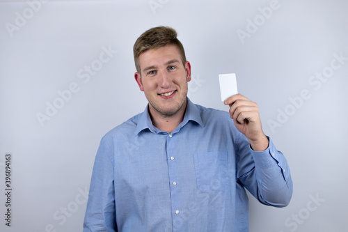 Business young man wearing a casual shirt over white background holding white card