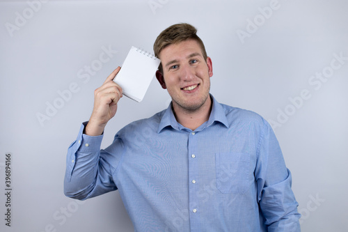 Business young man wearing a casual shirt over white background holding a blank notebook