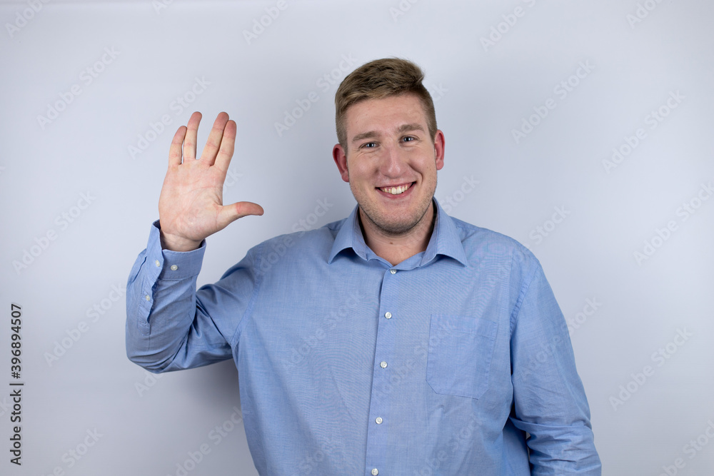 Business young man wearing a casual shirt over white background doing star trek freak symbol Business young man wearing a casual shirt over white background doing star trek freak symbol