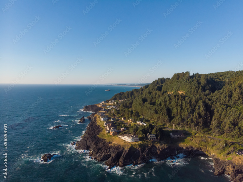 Aerial drone panoramic view of forest rocky cost in the ocean waves. Beautiful sunny weather. Amazing natural landscape. View from above.