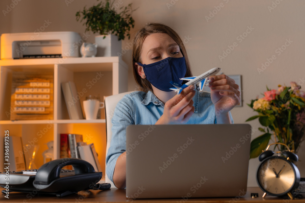 Tired woman siting in the office in face mask to protect and take care of their health and dreams about travel. Concept of coronavirus pandemic in the world. Tired woman siting in the office in face mask to protect and take care of their health and dreams about travel. Concept of coronavirus pandemic in the world.