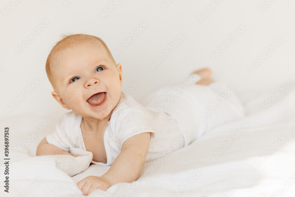 Portrait of beautiful baby girl laying on comfortable bed at home, wonderful cute toddler look around with big interest, smiling, childhood and childcare concept