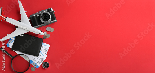 Flat lay composition with toy airplane and travel items on red background. Space for text