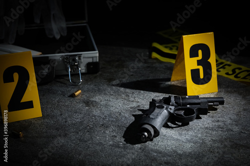 Shell casing  gun and crime scene marker on grey stone table