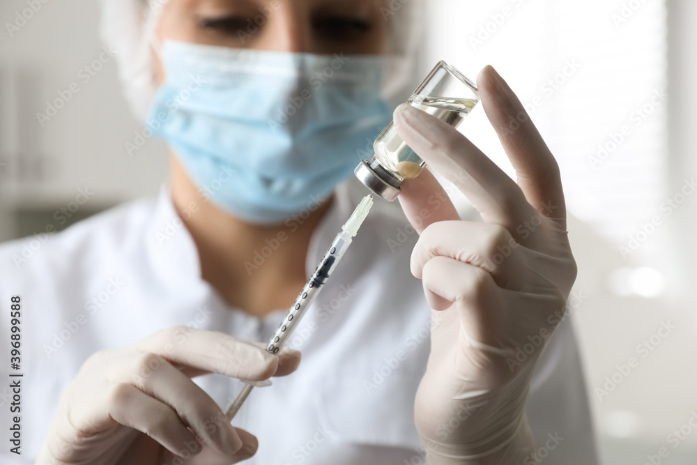 Doctor filling syringe with medication in clinic, focus on hands. Vaccination and immunization Doctor filling syringe with medication in clinic, focus on hands. Vaccination and immunization