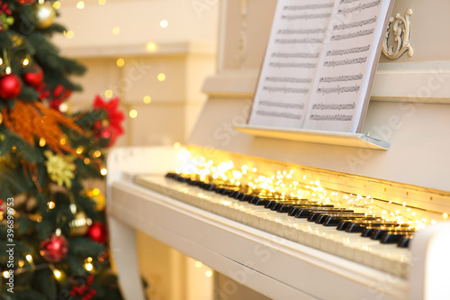 White piano with festive decor and note sheets indoors. Christmas music © New Africa
