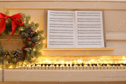 Wall Mural White piano with fairy lights, beautiful Christmas wreath and music sheets, clos