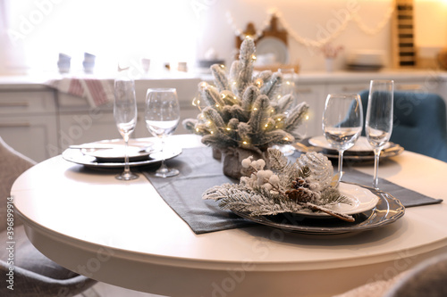 Table with set of dishware and beautiful Christmas decor in kitchen. Interior design