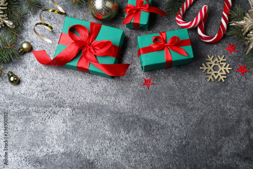 Flat lay composition with gift boxes and Christmas decorations on grey textured table, space for text