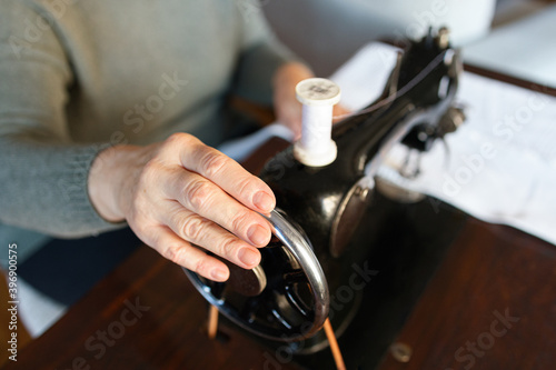 Old woman hands using an old sewing machine