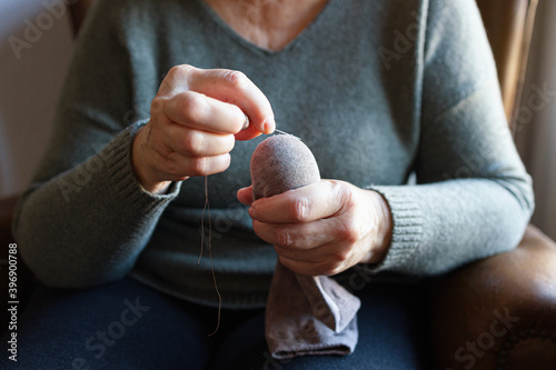 Bilde på lerret Old woman mending a sock at home