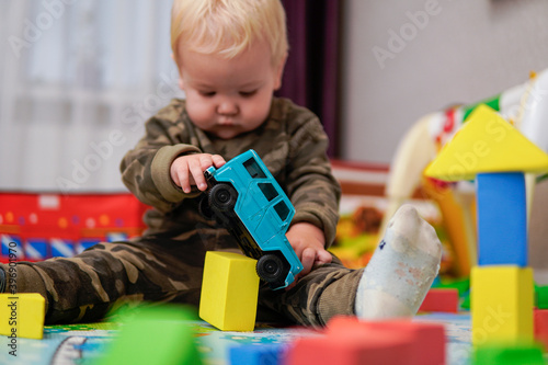 Little boy with blond hair playing with blue car