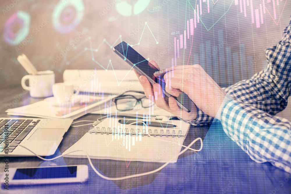 Fototapeta premium Double exposure of man's hands holding and using a digital device and forex graph drawing. Financial market concept.