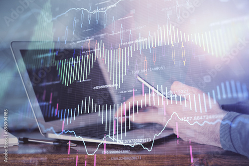 Double exposure of man's hands holding and using a digital device and forex graph drawing. Financial market concept. © peshkova