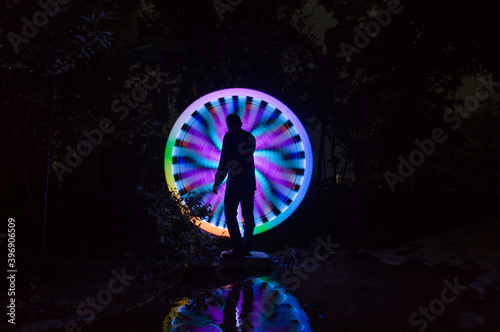 One person standing alone against creative color circle light painting as the backdrop 
