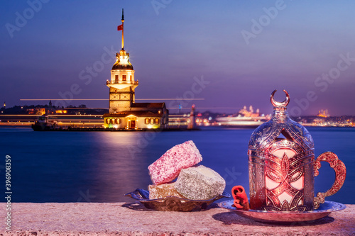 Magnific view of Maiden's Tower (aka Kiz kulesi) at night time on the background and turkish coffee with colorful turkish delight on the front. Istanbul attractions. photo