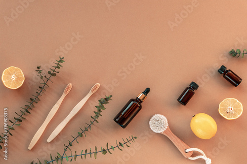 Wooden face brush, toothbrushes, cosmetic oil and serum. Eco-friendly hygiene products. Beige background, top view