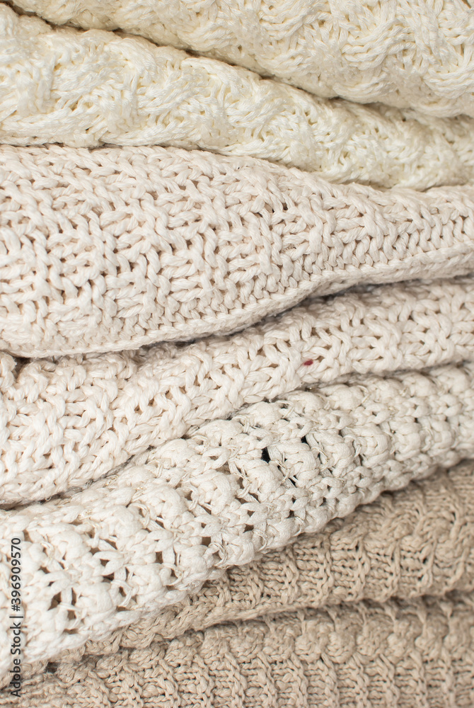 Stack of white cozy knitted sweaters. Knitted background, texture, pattern. Closeup of sample with knitting weave. Winter season. Stack of white cozy knitted sweaters. Knitted background, texture, pattern. Closeup of sample with knitting weave. Winter season.