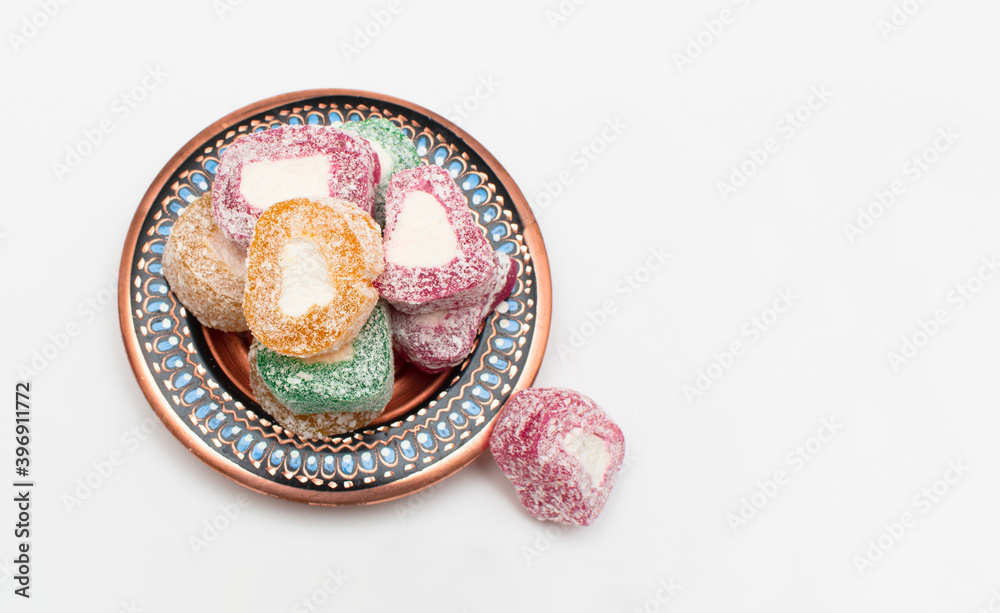 Fototapeta premium Colorful Turkish delight (aka lokum) in traditional bowl isolated on white background. Middle Eastern dessert popular in the month of Ramadan. 