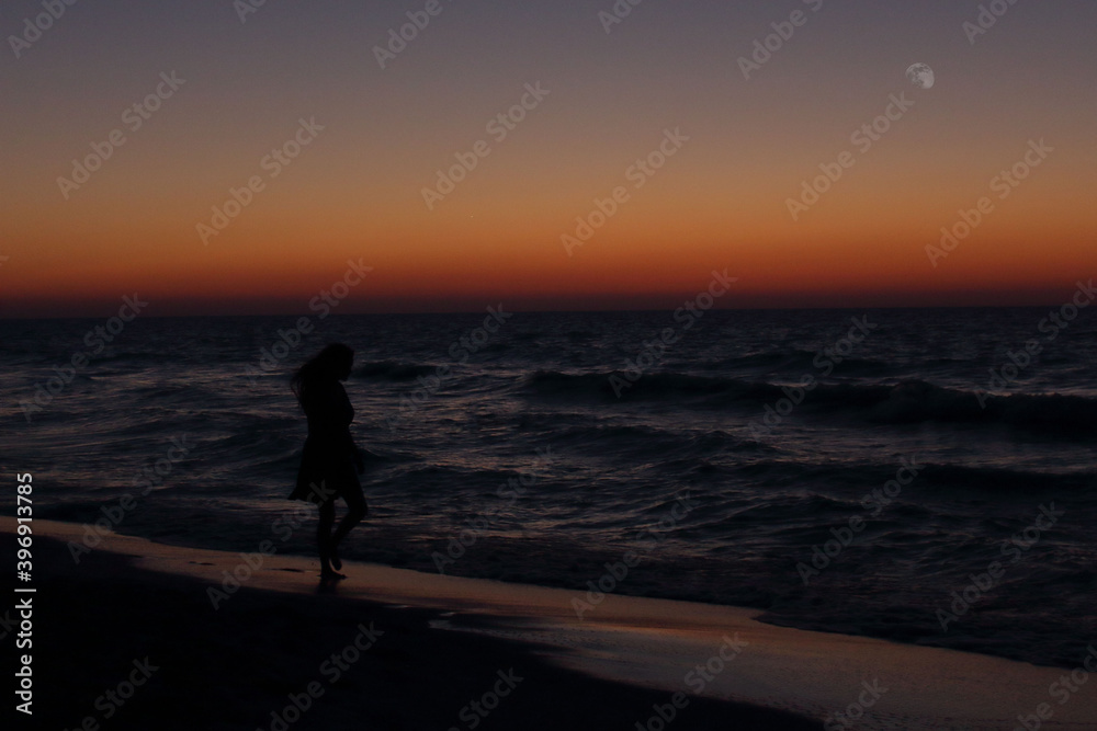 person walking on the beach at sunset