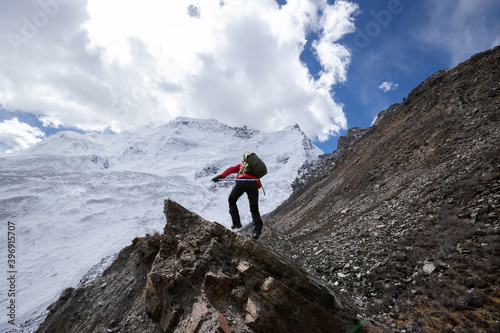 Woman hiker walking on winter mountain top cliff edge