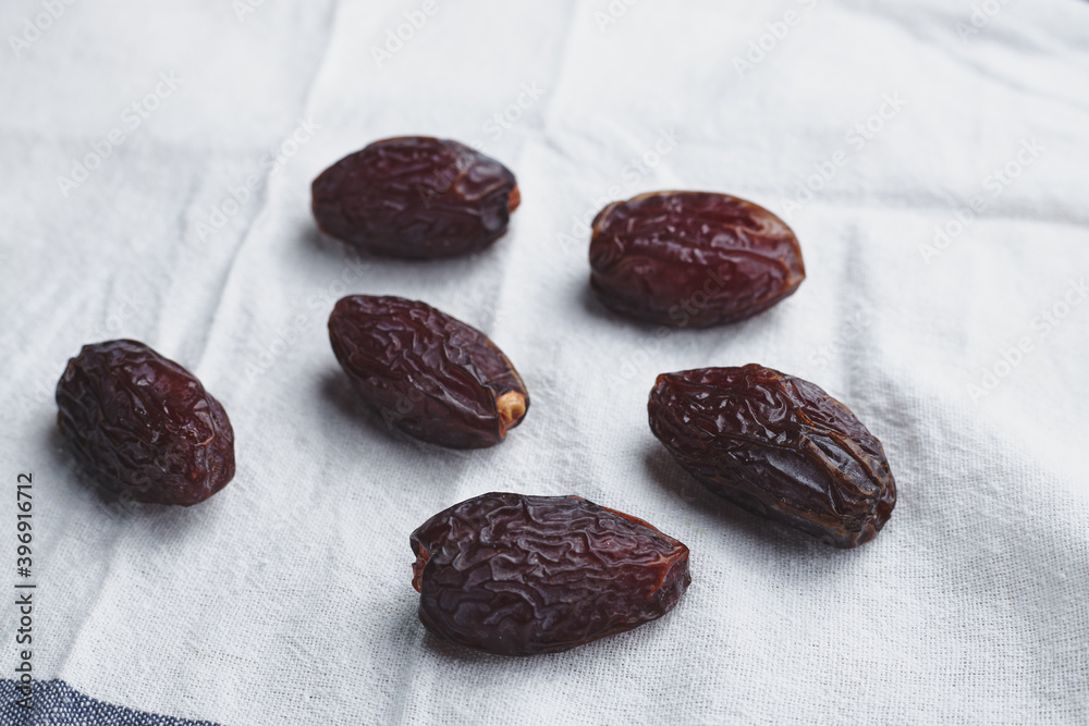 Obraz premium fruit date palm on a white tablecloth and craft paper. symbol of abundance in Ramadan. sweet berries from a tree. several sweet dried berries. raw food