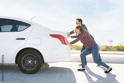 Couple moving their dead vehicle to the side of the road