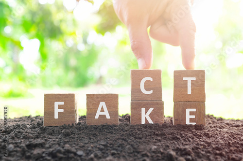 Obraz na płótnie Fake news versus facts concept. Hand changing fake wooden blocks to word fact in natural background. w salonie
