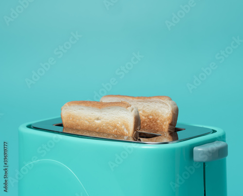 Toaster with bread slices on mint green background