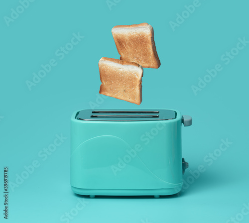 Bread popping up of toaster on mint green background