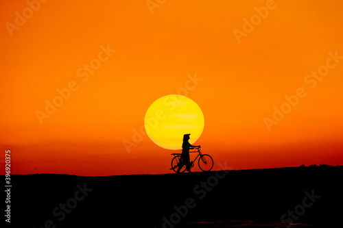 Silhouette Vietnam girl with bicycle go to travelling with beautiful sun sky background.