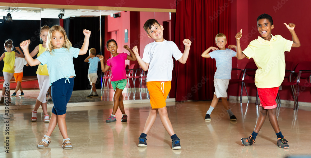 Group of smiling little boys and beautiful girls having the dancing class in a studio
