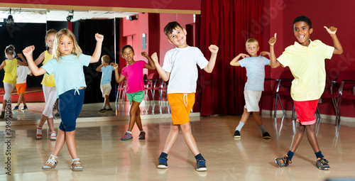 Group of smiling little boys and beautiful girls having the dancing class in a studio
