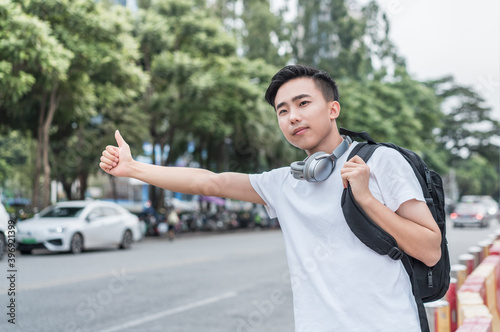 Asian young man is hailing a taxi on the street