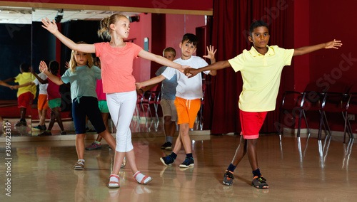 Smiling cheerful children primary school trying dancing salsa dance in modern studio