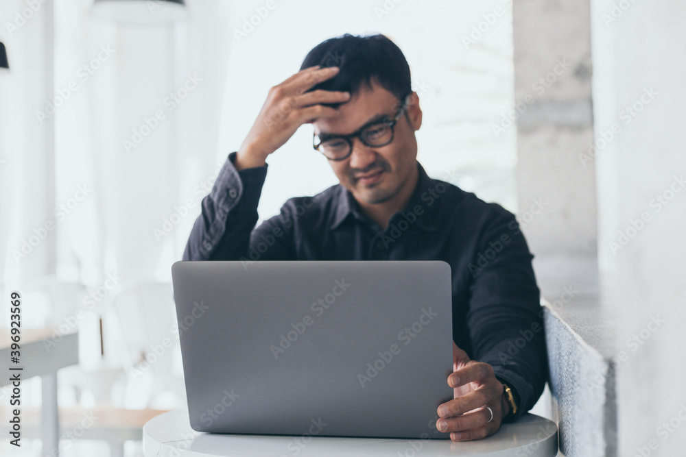 sad depression serious people from work stress concept.asian man feeling tired suffering using computer working work place.concept global economic and health problems sad depression serious people from work stress concept.asian man feeling tired suffering using computer working work place.concept global economic and health problems
