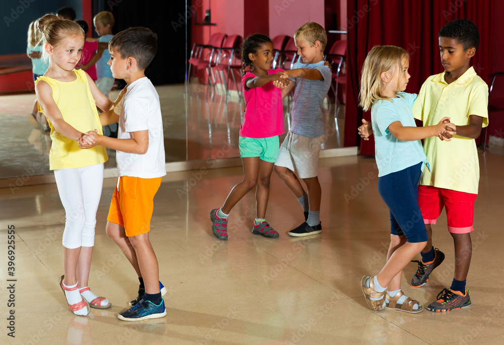 Group of positive children dancing salsa dance in modern studio