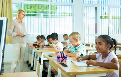 Portrait of focused aframerican preteen schoolgirl writing exercises in workbook in classroom during lesson