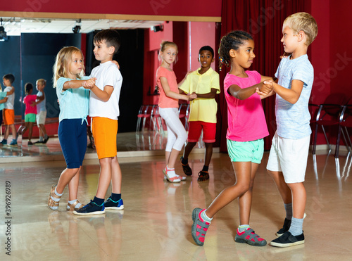 Group of happy smiling childrens trying dancing with partner in classroom