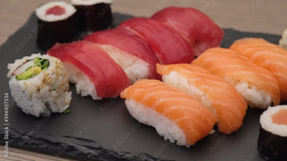 Sushi nigiri salmon, nigiri tuna, hosomaki and uramaki rotating on a plate
