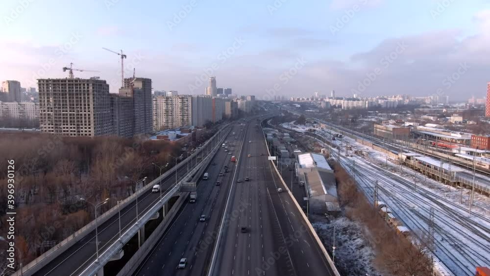 Aerial view flight over a high-speed highway in a big city at dawn. Movement of cars through the streets of the city Aerial view flight over a high-speed highway in a big city at dawn. Movement of cars through the streets of the city