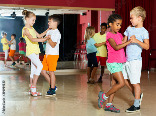 Focused kids primary school trying dancing of partner dance in modern studio